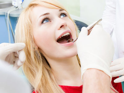 A woman in a dental chair receiving oral care, with a dentist performing the procedure.