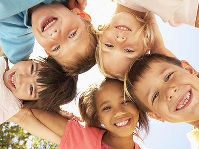 A group of children in a joyful pose, smiling and looking towards the camera.